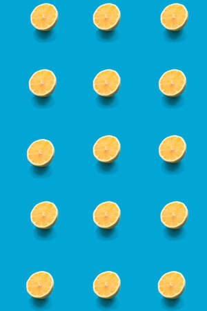 Pattern lemon fresh yellow half slice close up on bright blue color background. Trendy summer minimal concept. Flat lay. Selective soft focus.の写真素材
