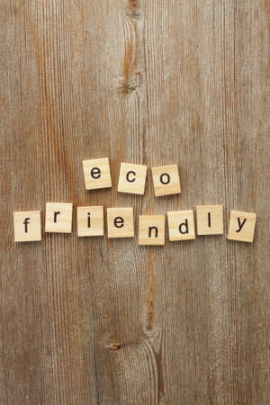 Inscription text word eco friendly made of letters on wooden blocks on old rustic wood background. Ecology concept. Flat lay. Top view. Close up. Selective soft focus. Text copy space.の写真素材