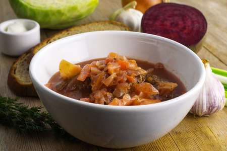 Borscht russian ukrainian traditional vegetable cabbage beetroot red soup in white bowl on natural wooden table background. Close up. Selective focus. Copy spaceの写真素材