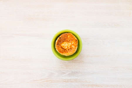 Homemade cottage cheese pancakes syrniki stack on round green bowl on white rustic table backgroundの写真素材