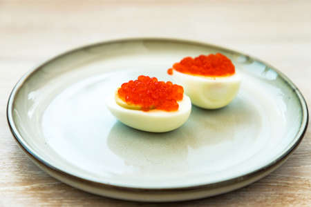 Red caviar stuffed halved eggs traditional Russian snack served on blue gray plate. Close up. Selective focus. Copy spaceの写真素材