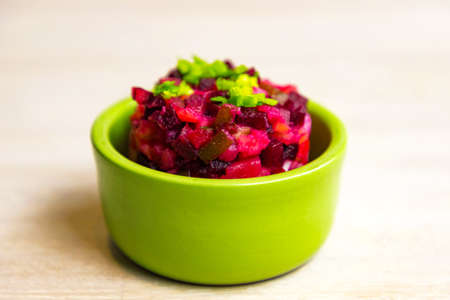 Homemade Russian beet salad vinegret in green bowl on white table background. Close up. Selective focus. Copy spaceの写真素材