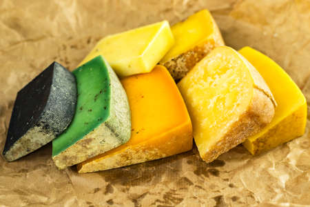 Assorted craft cheeses of different types and colors on oiled, crumpled parchment paper