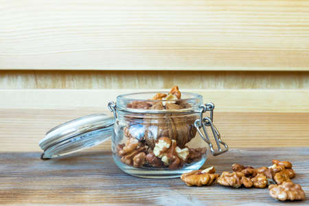 Walnut nuts in glass jar on wooden background. Close-up. Copy space. Selective focus.