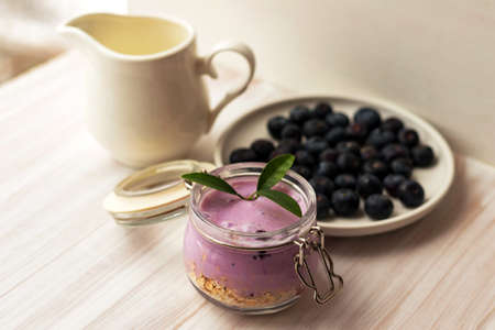 Oat flakes granola or muesli with homemade yogurt smoothie, fresh blueberry and ceramic jug milkの写真素材