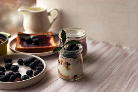 Rolled oats muesli granola parfait, overnight oatmeal in glass jar, toasted bread, blueberry jamの写真素材