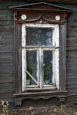 Brown carved platband cracked glass window of old traditional russian wooden houseの写真素材