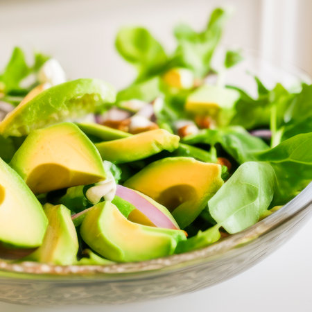 Avocado and vegetables salad bowl on white kitchen table, wall background close up food photographyの素材