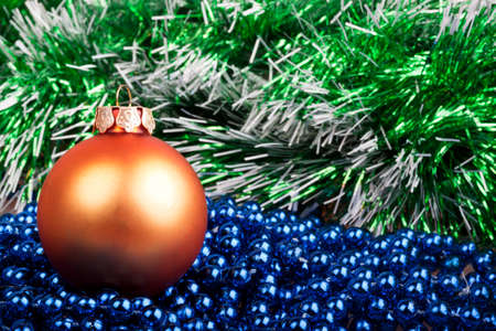 orange Christmas ball and blue beads on a background of green garlandの写真素材