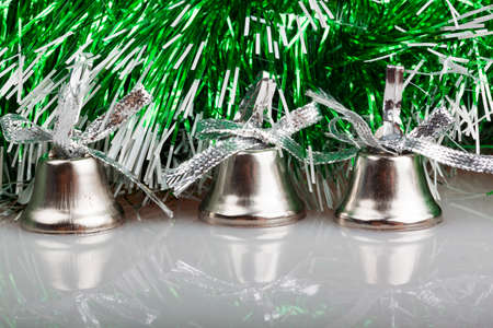 three silver bells on the background of green garlandの写真素材