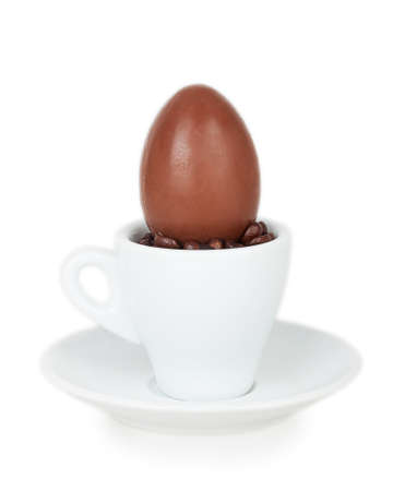 chocolate egg on a white cup and saucer isolated on white backgroundの写真素材