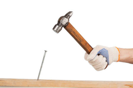 male hand in working glove hits the nail into a wooden board on the white backgroundの写真素材