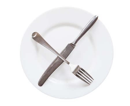 Empty white plate with knife and fork isolated on white backgroundの写真素材