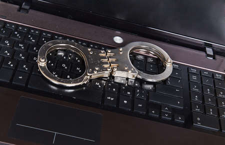 Metal handcuffs on black laptop keyboardの写真素材