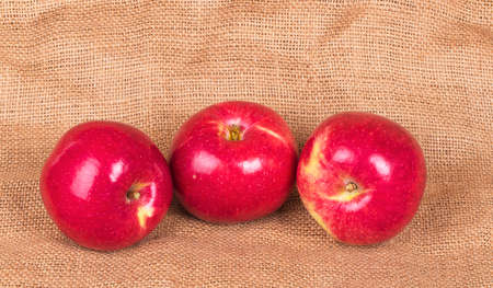 Three red apples on sackclothの写真素材