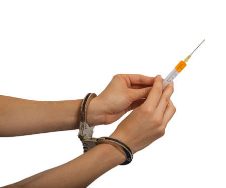 Female hands in handcuffs holding syringe isolated on white backgroundの写真素材