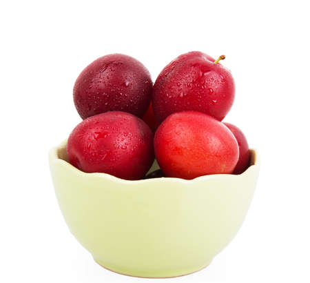 Fresh plums in green deep bowl isolated on white backgroundの写真素材