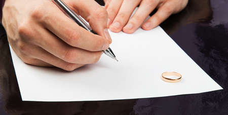 Closeup of male hand signing divorce papersの写真素材