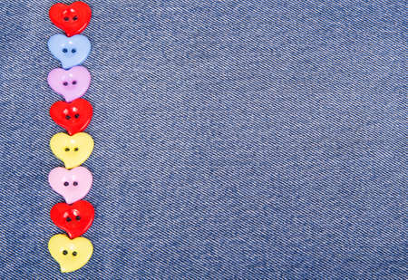 Multi-colored buttons in the shape of hearts on jeans backgroundの写真素材