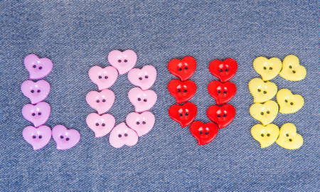 Multi-colored buttons in the shape of hearts on jeans backgroundの写真素材