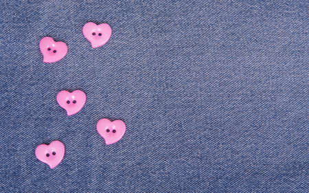 Pink buttons in the shape of hearts on jeans backgroundの写真素材