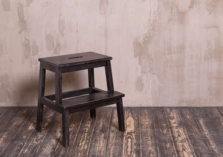 Black wooden chair in nterior room with gray decorative plaster wall and dark wooden floorの写真素材