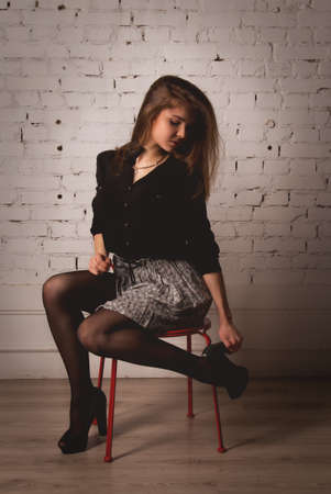 Beautiful sexy brunette woman on a chair in the studioの写真素材
