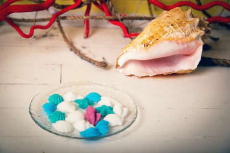 Figurines made of sugar in a glass dish with a large seashellの写真素材