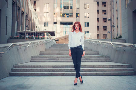 Fashion redhead young woman walking outdoor on streetの写真素材