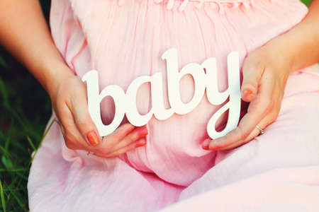 Label "Baby" in the hands of a pregnant woman outdoorsの写真素材