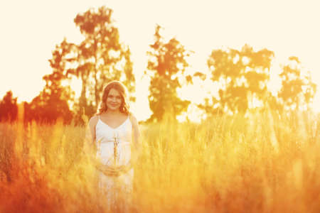 Beautiful pregnant woman relaxing outside in the fieldの写真素材