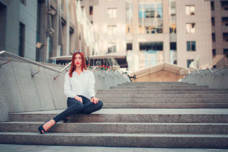 Fashion redhead young woman in sunglasses walking outdoor on streetの写真素材