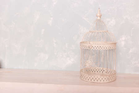 white bird cage on the wooden floor against the backdrop of a blue wallの写真素材