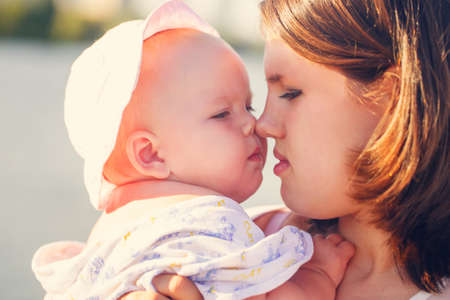 mother and daughter touching noses on the river in the summerの写真素材