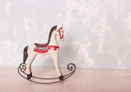 toy rocking white horse on the wooden floor against the backdrop of a blue wallの写真素材