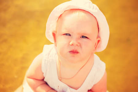 Baby girl in panama looking in camera outdoors in sunlightの写真素材