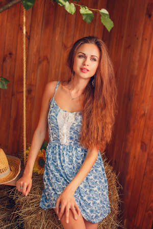 Portrait of sexy young woman sitting on the hay in the gardenの写真素材