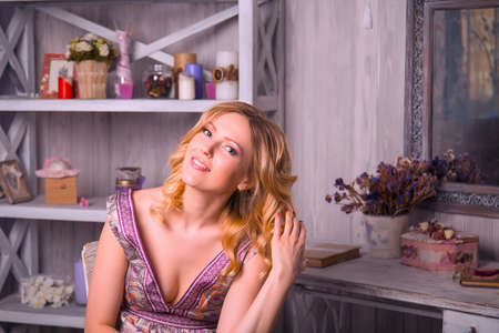 Beautiful blonde woman in the interior studio sits on a chairの写真素材