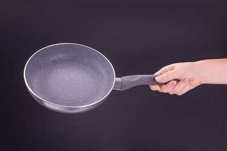 hand holding clean empty pan on a black backgroundの写真素材