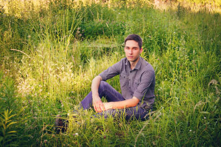 Portrait of a young man on nature in the grassの写真素材