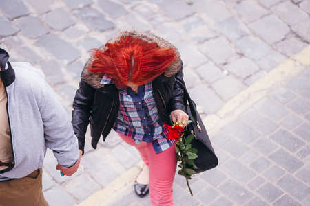 man gave a woman a rose, and leads her by the hand. She holds a rose in handの写真素材