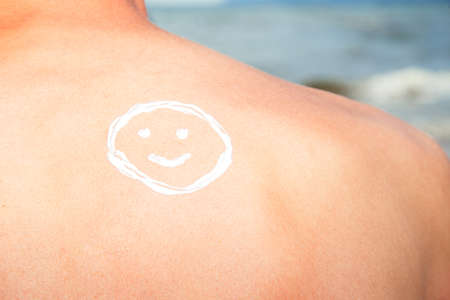 Lotion man with sunscreen smiley above sea backgroundの写真素材
