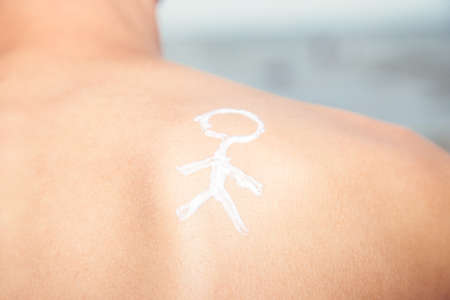 Lotion man with sunscreen with a little man on the sea backgroundの写真素材