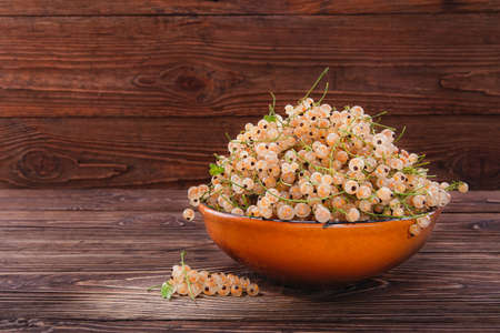 White currants in clay bowl on a wooden backgroundの写真素材