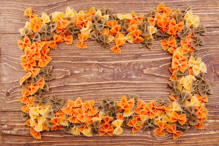  dry butterfly pasta of different colors on a wooden backgroundの写真素材
