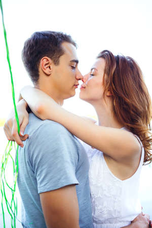 Beautiful cheerful happy couple looking at each other, touching noses and cover near the riverの写真素材
