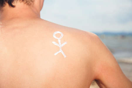 Lotion man with sunscreen with a little man on the sea backgroundの写真素材