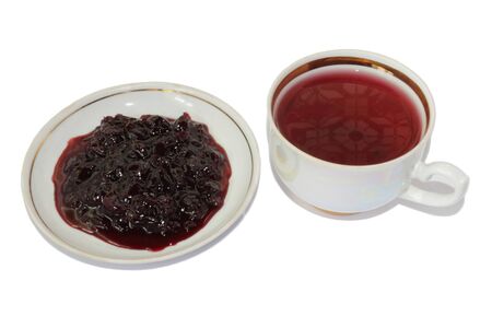 Cherry jam on saucer and a cup of tea Karkade on a white backgroundの写真素材