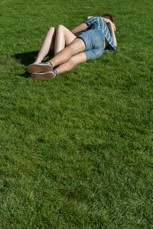 Close-up of legs of lying pair on the green grassの写真素材