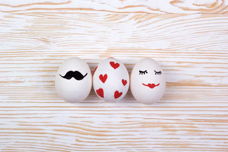 Funny eggs with painted faces on light wooden backgroundの写真素材